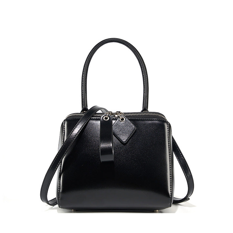 Black handbag with a strap on a white background