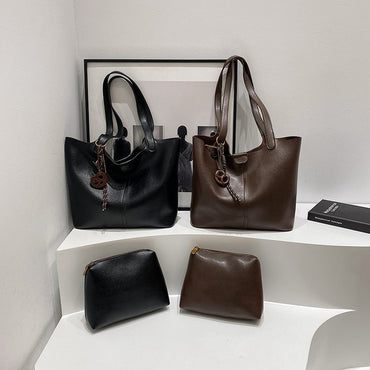 Black and brown handbags on a white shelf with a framed picture in the background.