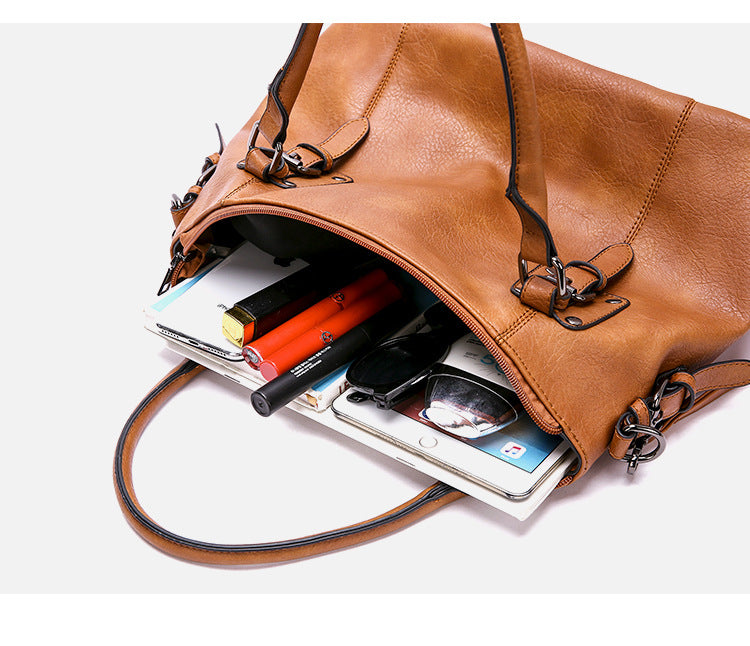 Brown leather bag with items like a smartphone and wallet on a white background