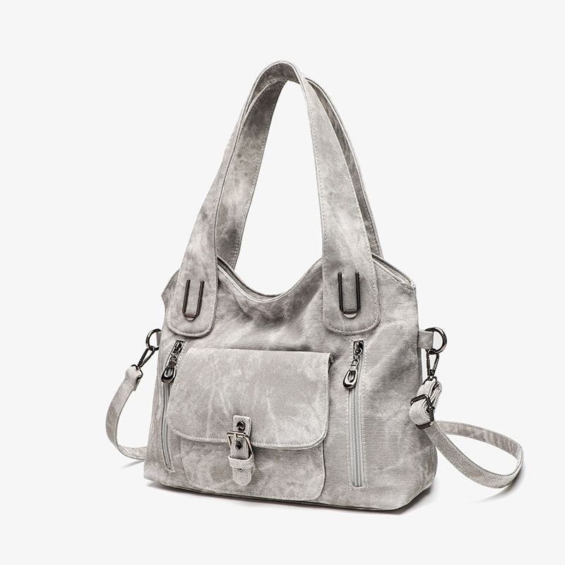 Gray handbag with multiple pockets and straps on a white background
