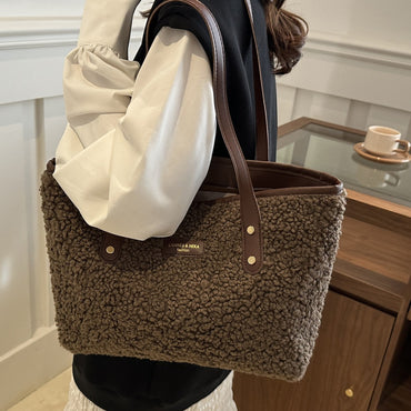 Brown textured handbag held by a person in a casual setting
