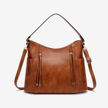 Brown leather handbag with shoulder straps on a white background