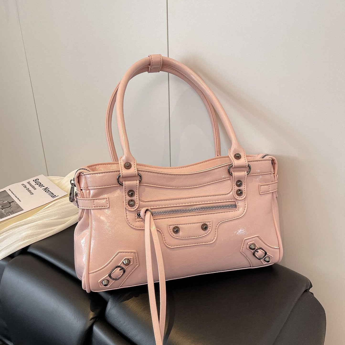 Pink handbag with visible brand name on a black surface against a light gray wall.
