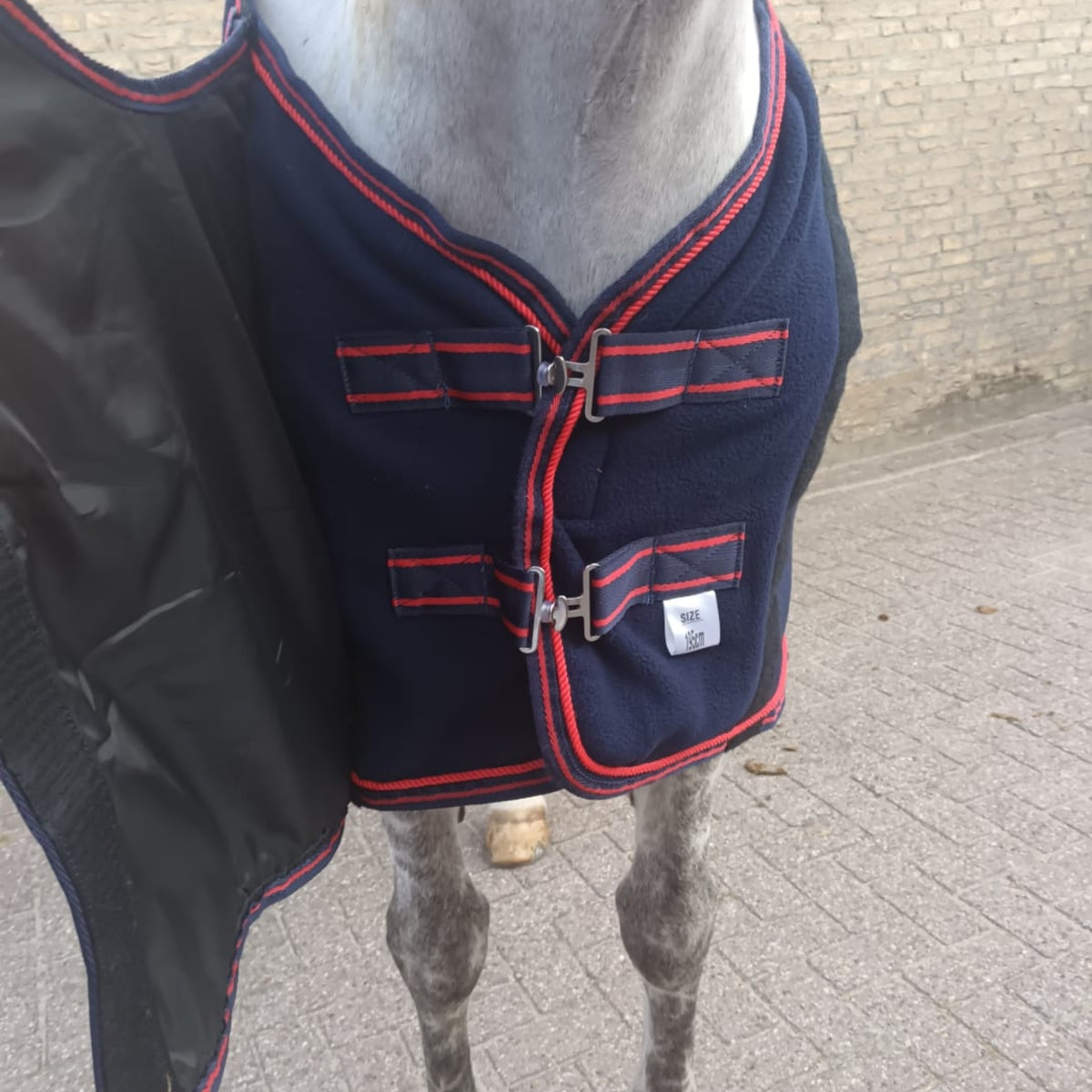 Double front closure system with male and female fastening on fleece horse rug, providing secure fit and easy adjustment.